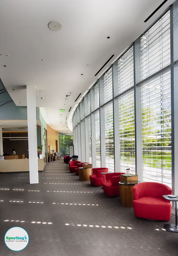 Commercial carpet cleaning Rochester NY: bright office lobby with carpeted floor and red lounge chairs