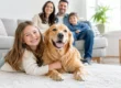 Smiling family with two children and a golden retriever relaxing on a clean rug in a bright living room